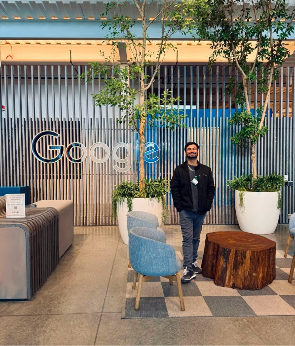 A man standing in an office lobby beside a large Google sign