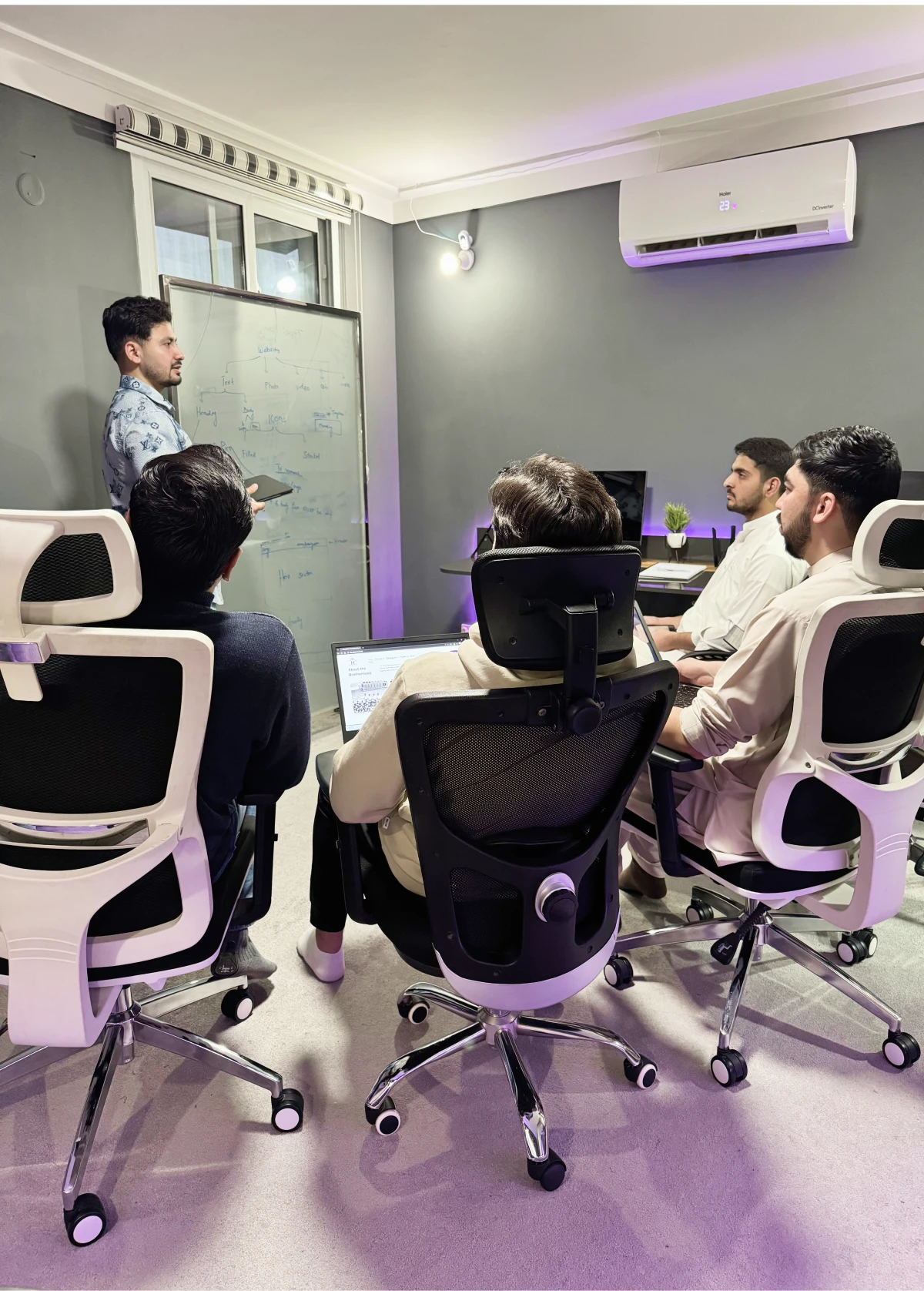 courses A group of people sitting in a room with a whiteboard and a man standing in front of it, likely teaching a course
