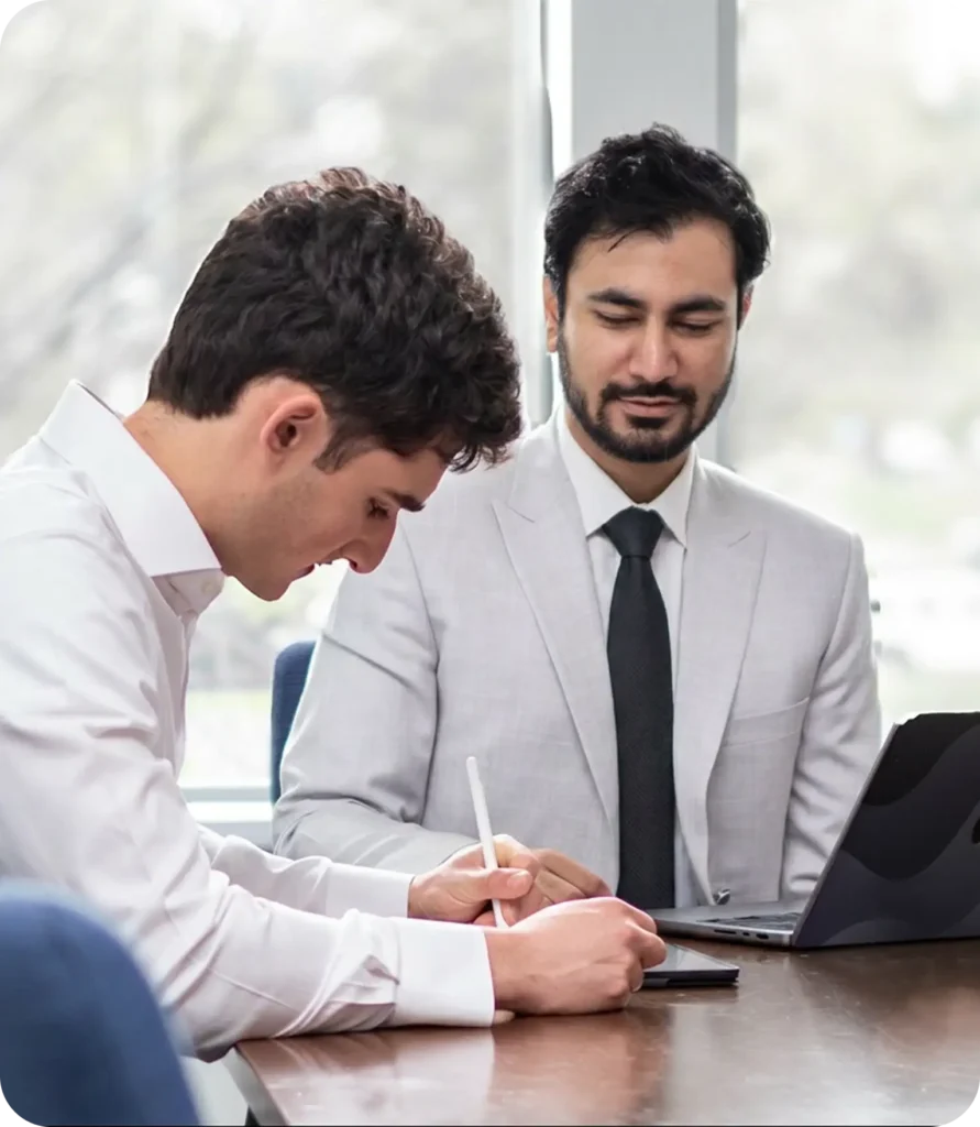 Two men reviewing a project at a table with a laptop