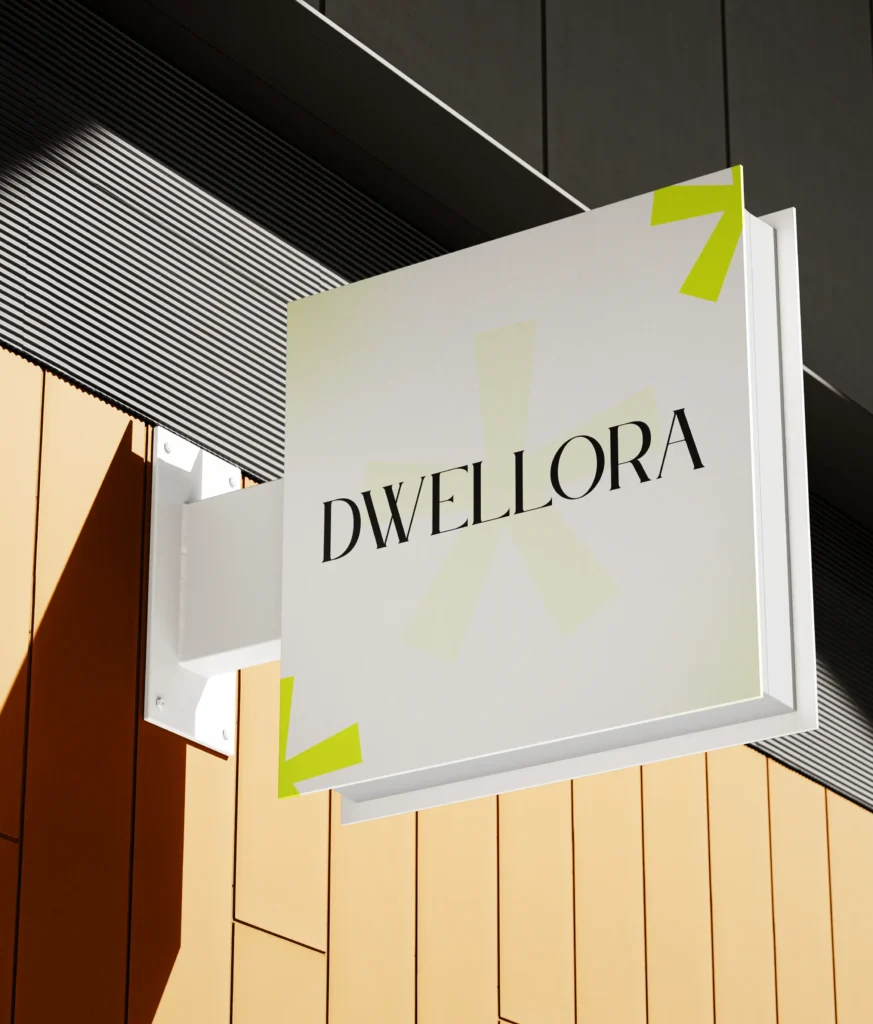 A wall sign reading Dwellora mounted on a building with wooden cladding