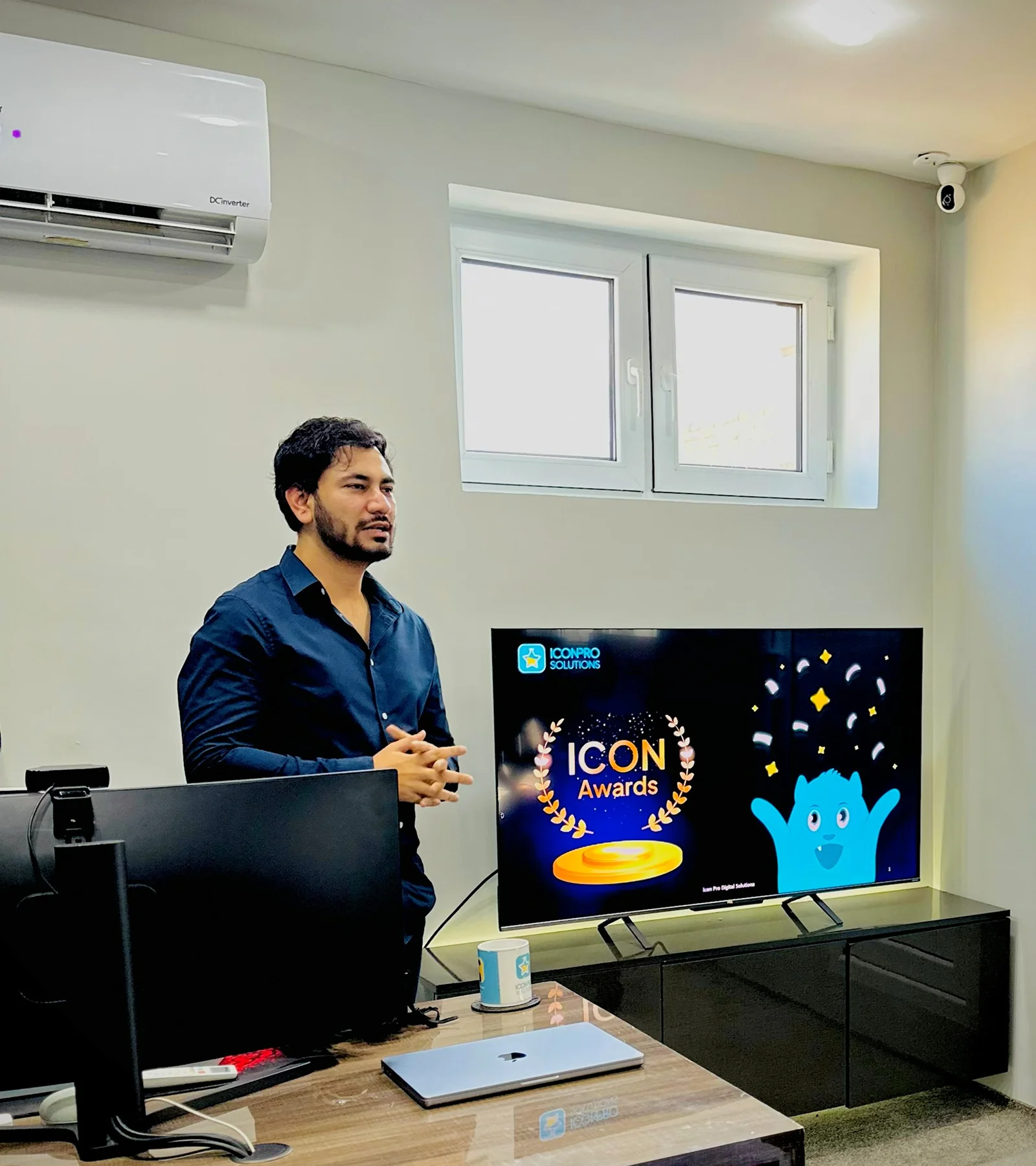 Waqar Hussain, Icon Pro Solutions CEO, presenting beside a screen showing an ICON Awards graphic