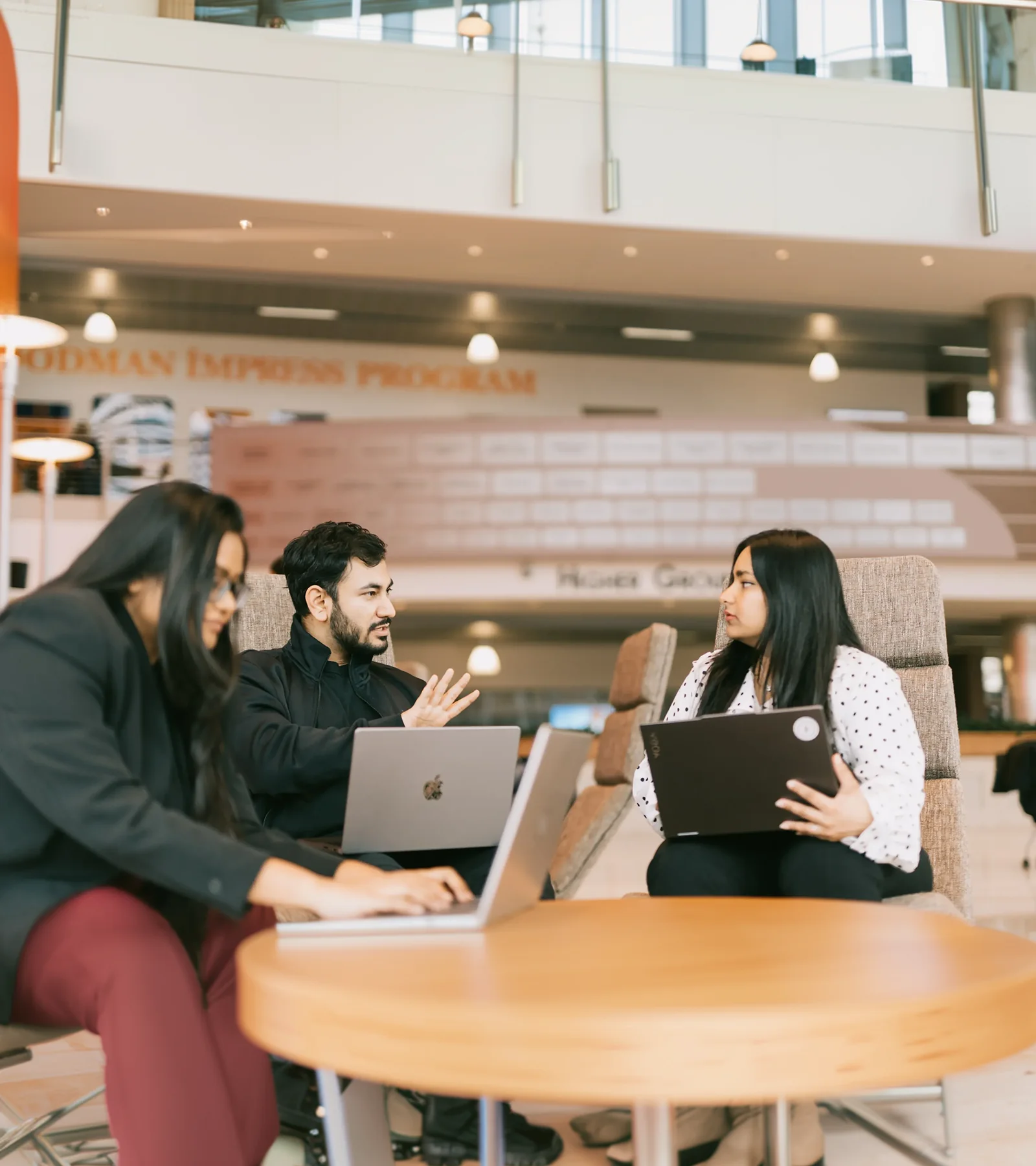 Waqar Hussain, Icon Pro Solutions CEO, working on a laptop with two colleagues around a round table in a university hall