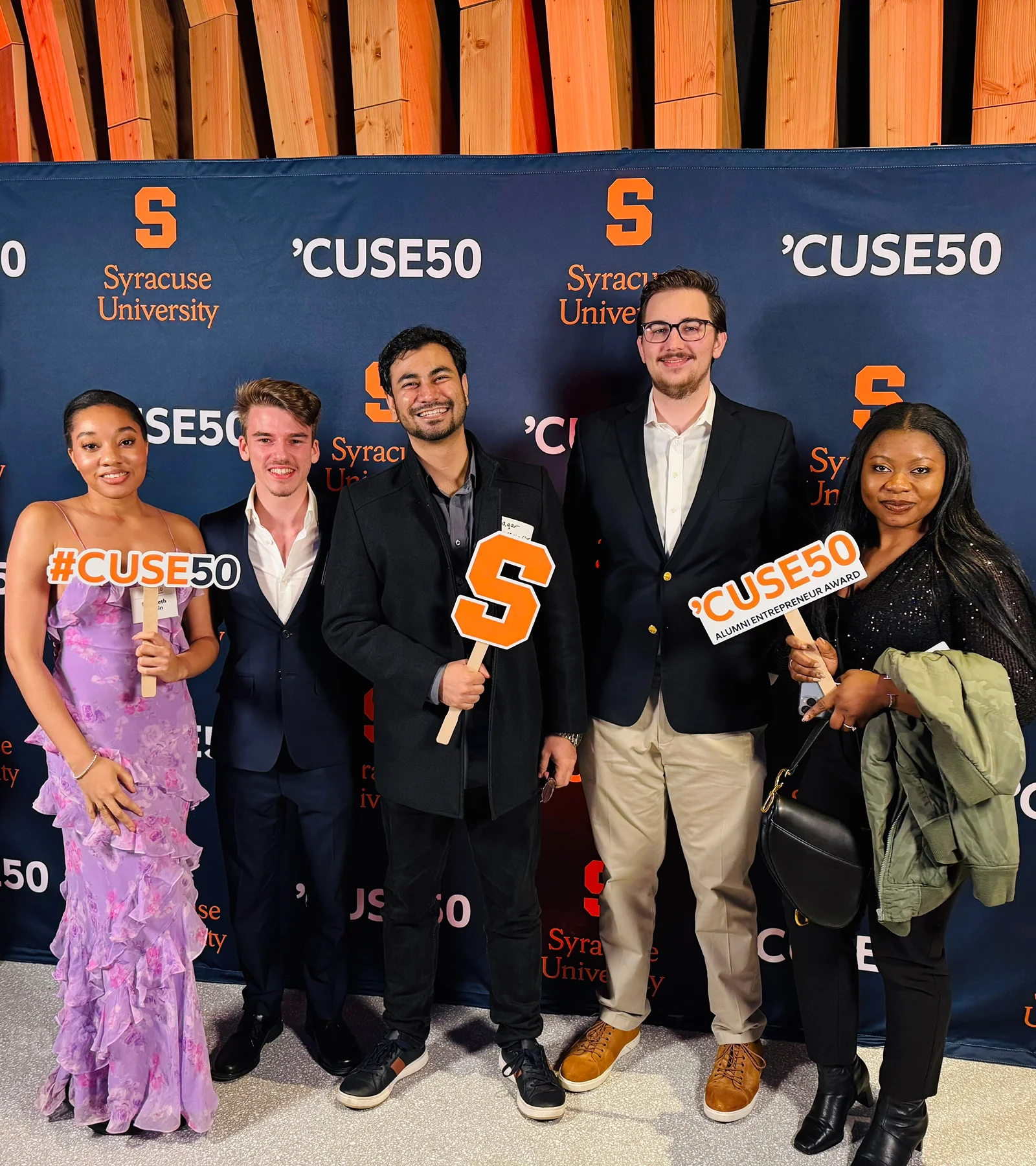 Waqar Hussain, Icon Pro Solutions CEO, with four others holding 'Cuse50 signs in front of a Syracuse University backdrop