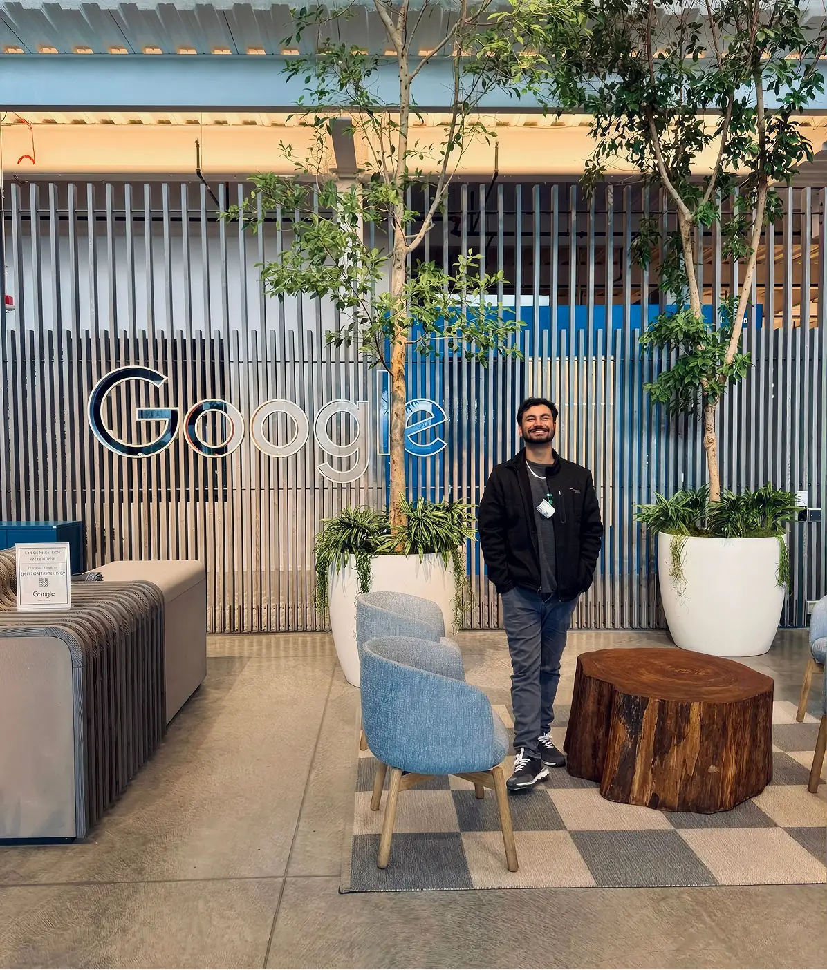 A man standing in an office lobby beside a large Google sign