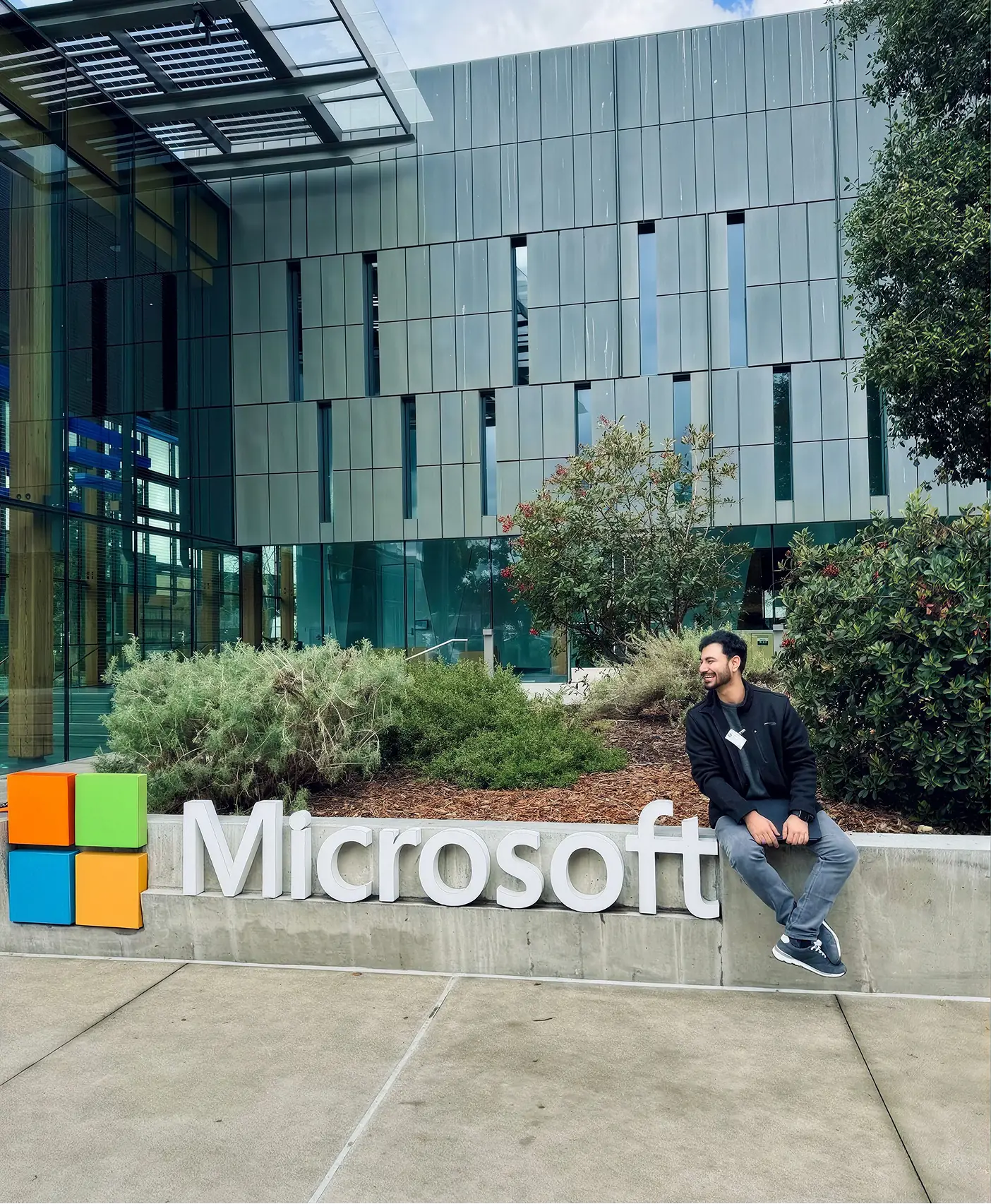 A man sitting on a Microsoft sign outside an office building