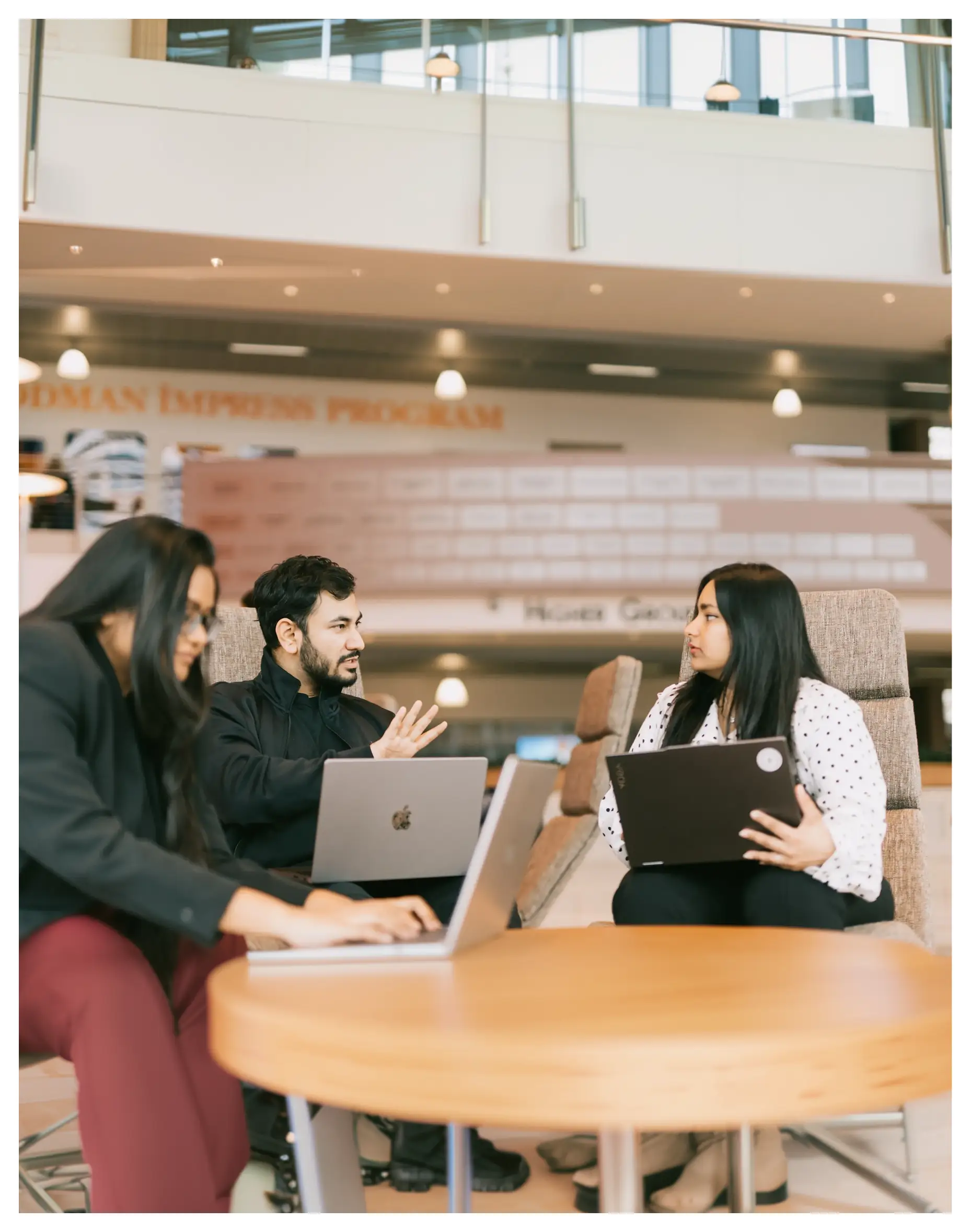 Three people working on laptops around a table