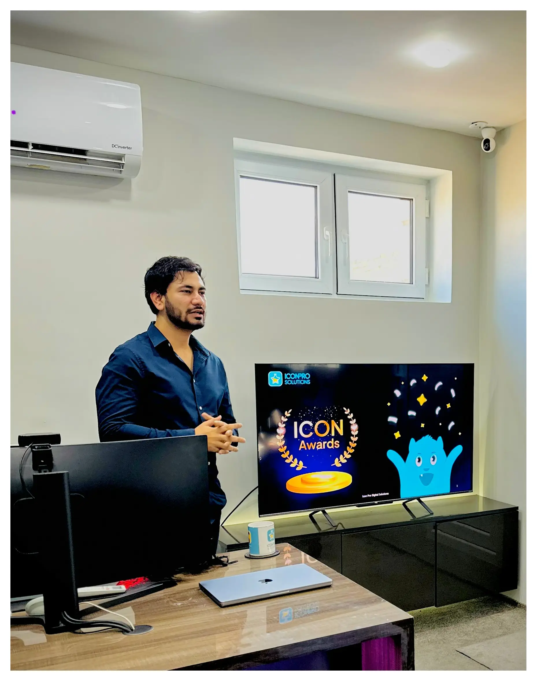 A team member in the office beside a screen showing the ICON Awards