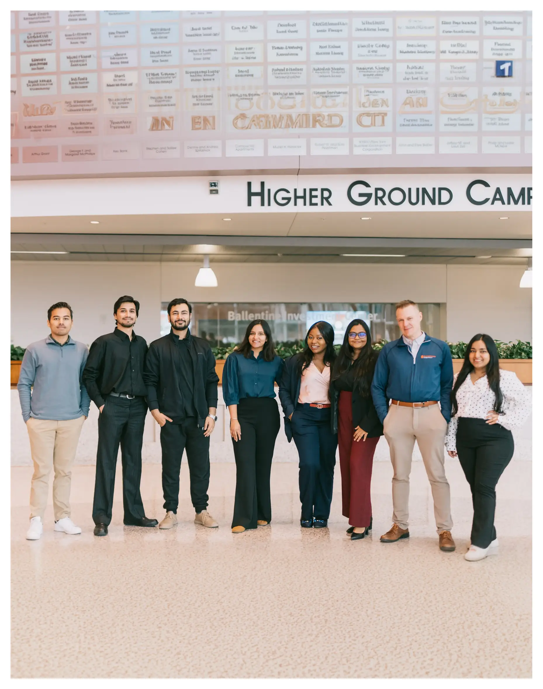 A group of eight people in front of the Higher Ground Camp sign